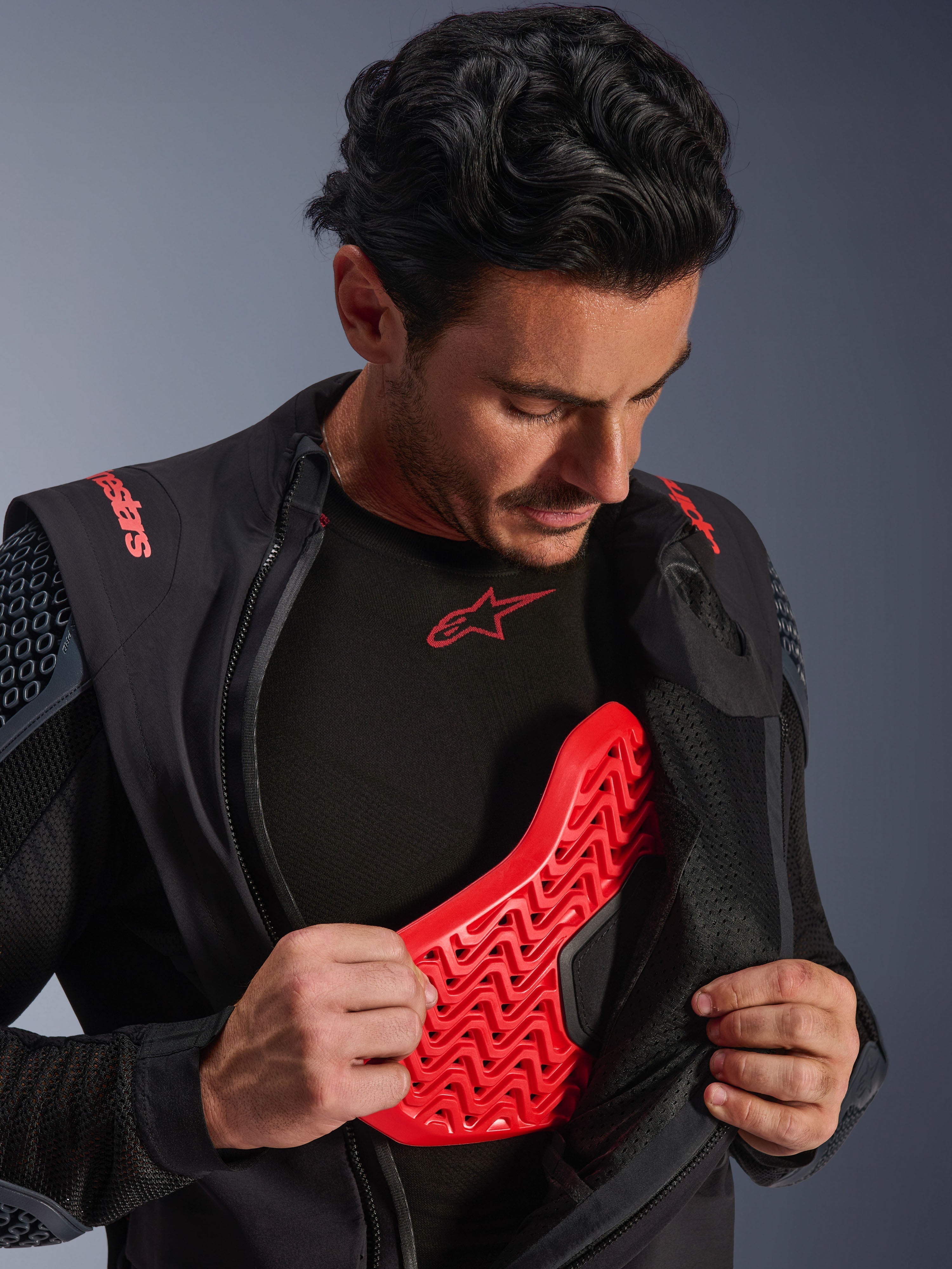 Alpinestars Halo Pro Drystar® XF Laminated Jacket in Black Dark Shadow, worn by a model and unzipped to reveal a red Nucleon Flex Pro chest protector, technical motorcycle jacket with integrated armor, adventure riding apparel.