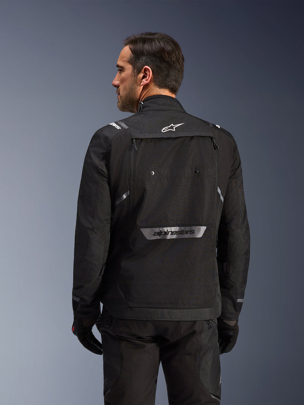 Rear view of the black Alpinestars Cusco Drystar® Jacket for men, featuring a large storage pocket and reflective branding.