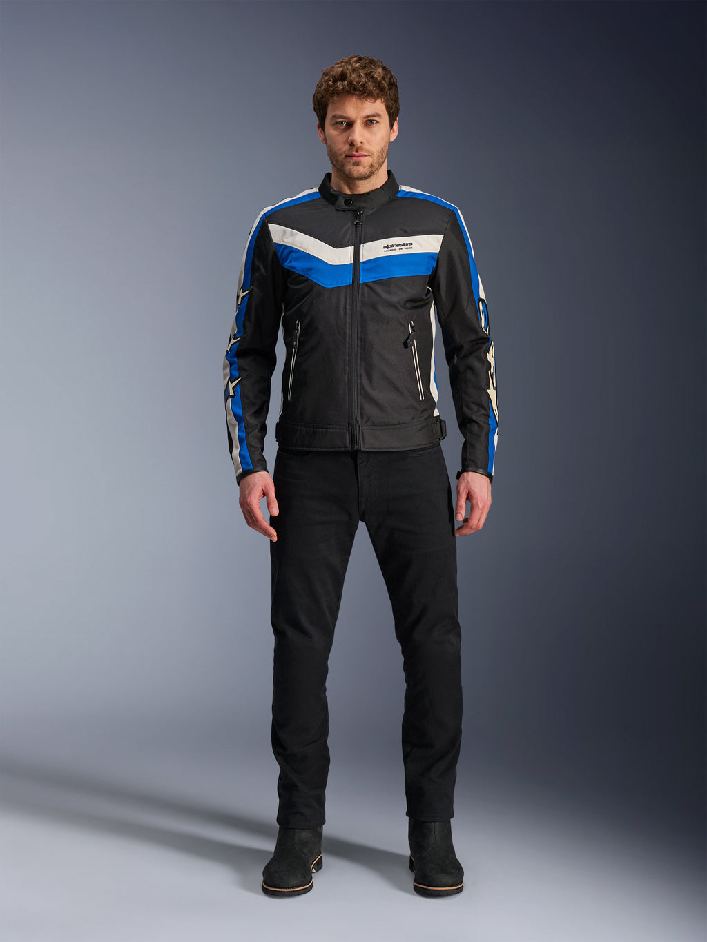 Alpinestars T-Dyno WR Jacket, Textile Motorcycle Jacket, Black Blue and Ecru, worn by male model with black pants and boots, featuring chevron stripes on the chest and heritage biker design