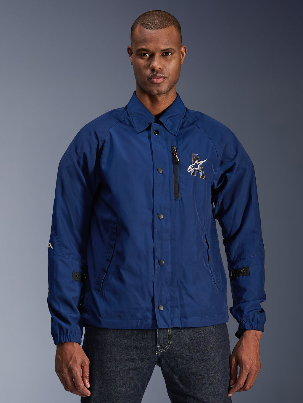 Alpinestars Revved WR Jacket, Men's Urban Motorcycle Jacket, Navy Blue, coaches style with fold-down collar and snap-button front, black zippered chest pocket, large 3D embroidery logo, adjustable sleeve tabs, satin finish water-resistant material