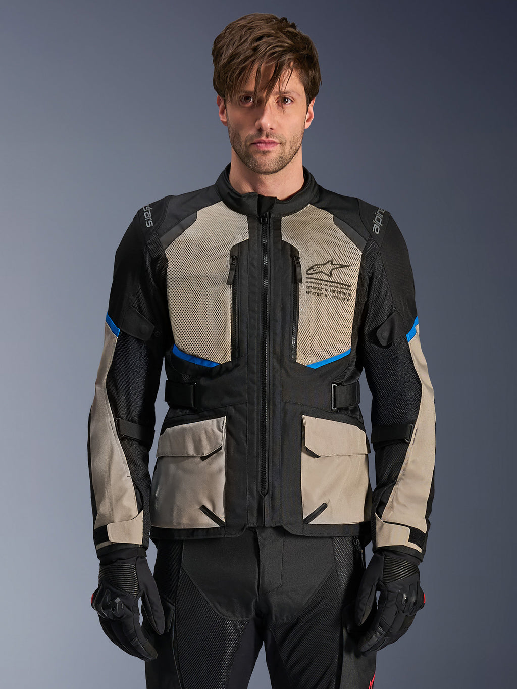 Alpinestars Andes Air Drystar Jacket, Adventure Touring Jacket, Black Laurel Gray and Bright Blue, worn by a model with black gloves, featuring large mesh chest panels for airflow, front cargo pockets, and blue accents, protective motorcycle touring gear