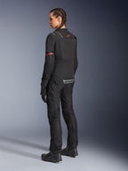 Female rider wearing black Alpinestars Stella Andes Air Drystar® Pants and matching Stella ST-2 Air Jacket, rear view showing technical textile construction and mesh panels, red star logo on the jacket back, paired with black riding boots and gloves.