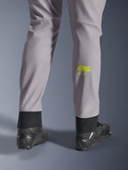 Alpinestars Aeroshell Pants, Mid Gray with Yellow Fluo Astars logo on the calf, shown from the back wearing black motorcycle shoes, featuring an elastic lower hem and a modern tapered silhouette