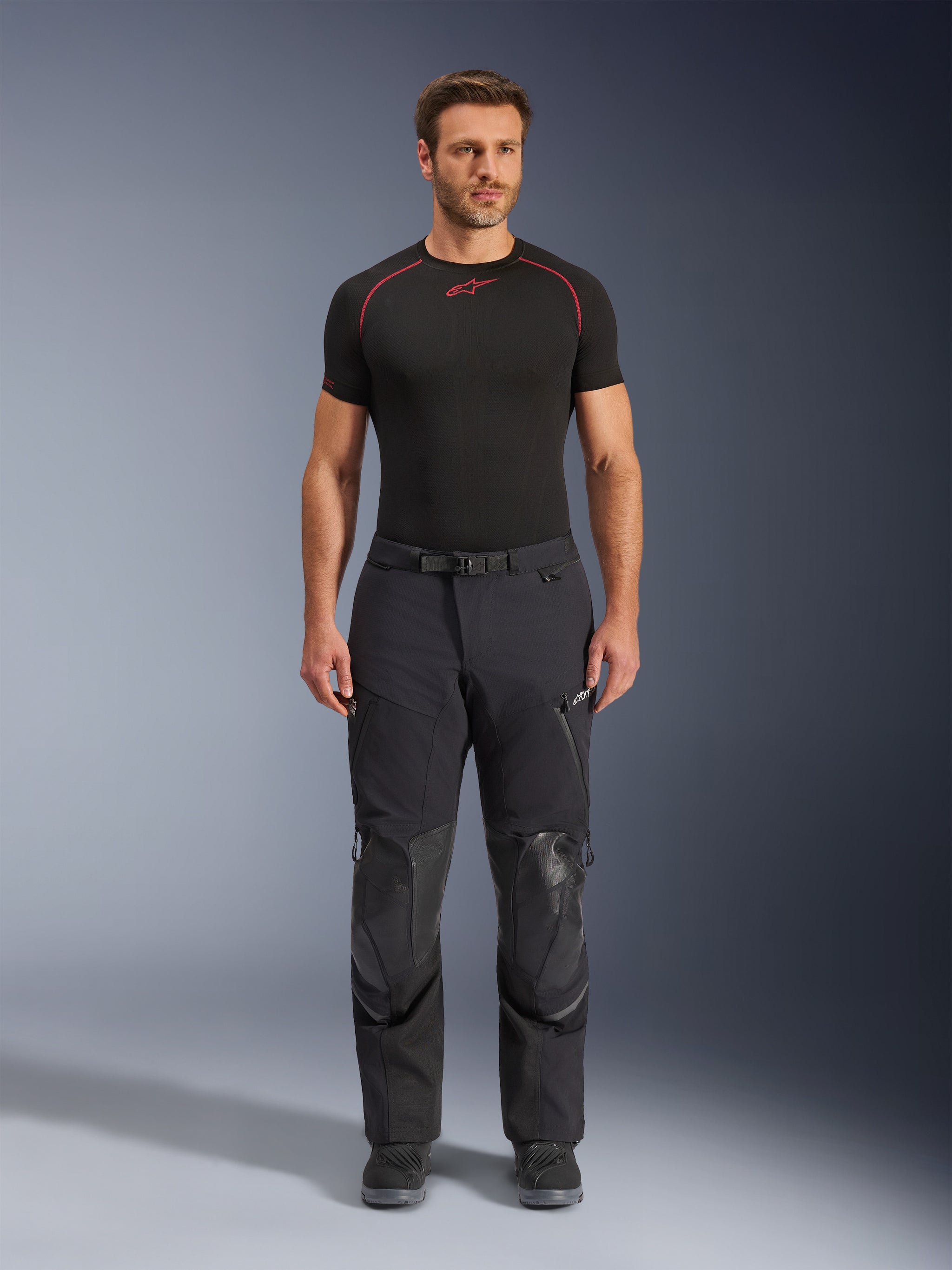 Alpinestars Andes Pro Drystar® XF Pants, Black Dark Gray adventure touring motorcycle pants, front view, featuring 3-layer laminated construction, integrated knee armor panels, waterproof zippered pockets, and magnetic waist buckle, styled with black riding boots.
