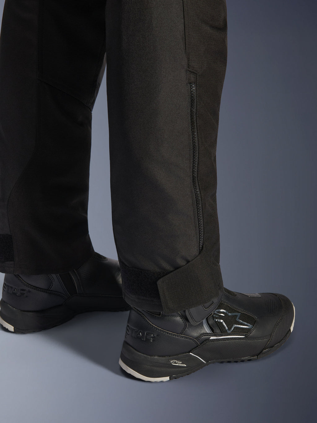 Alpinestars Stella Andes V4 Drystar® Pants, Black, close-up view of the lower leg and cuff, featuring a side zipper and adjustable hook-and-loop ankle strap, worn with black Alpinestars riding boots