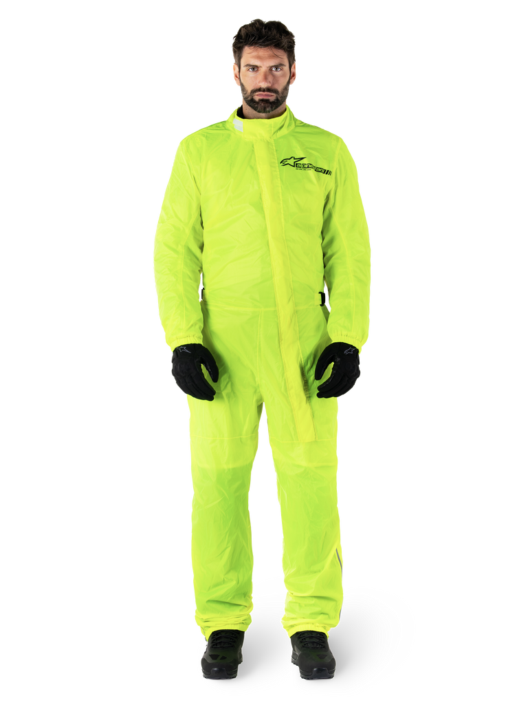 Alpinestars Hurricane Rain V2 Suit, Motorcycle Rain Suit, Yellow Fluo, male model wearing full-body protection with black gloves and boots, high collar with front storm flap, reflective logo on chest, high-visibility waterproof gear