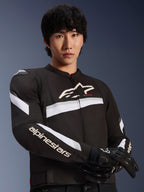 Alpinestars T-GP Plus R V4 Jacket, Black and White, worn by a male model, textile motorcycle jacket with white stripes across the chest and sleeves, Alpinestars logo on the chest, paired with black riding gloves