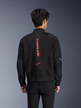 Rear view of a rider wearing the Alpinestars Flight Air Jacket in Black Bright Red, urban bomber-style motorcycle jacket with 3D mesh construction, featuring large vertical red Alpinestars branding and star logo on the back, street-inspired technical gear