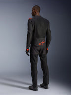 Male rider from the back wearing the Alpinestars Viper Air V4 Jacket, Black and Red Fluo, featuring an orange Astars logo on the lower back and shoulders, mesh textile construction, styled with matching black motorcycle pants and boots.