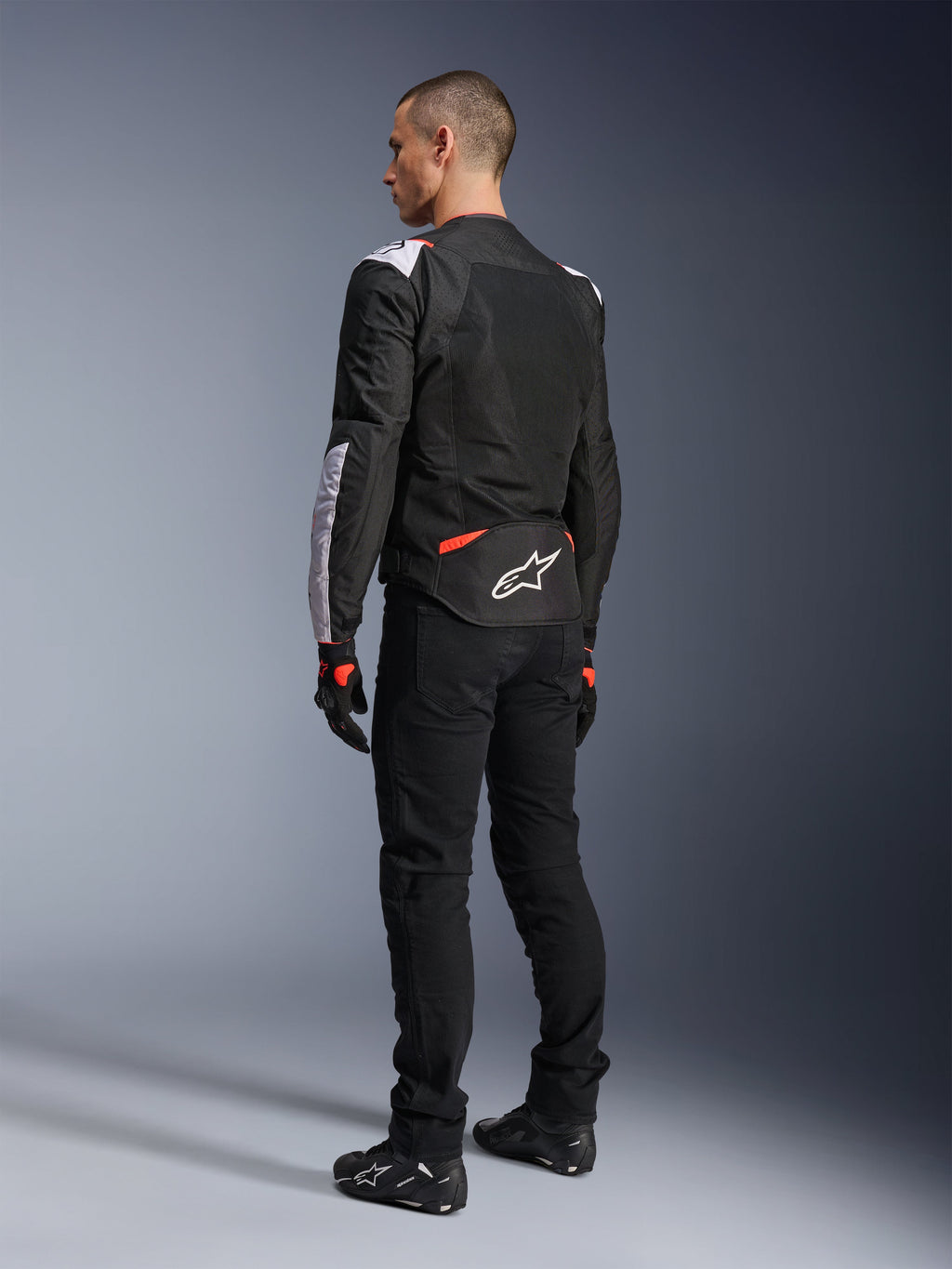 Alpinestars T-Sps Air V2 Jacket, Textile Motorcycle Jacket, Black White and Red Fluo, rear view on model, mesh paneling for ventilation, white Astars logo on lower back, styled with black riding pants and gloves