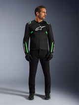 Man wearing the Alpinestars T-SPS Air V2 Jacket in Black Fluo Green, paired with black pants, gloves, and riding shoes, featuring a sport-cut design with white logos and mesh panels for a modern urban riding look.