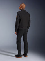 Alpinestars Bruiser Jacket, Urban Black Motorcycle Jacket, back view on a model, classic workwear styling, featuring pleated shoulder panels and Oscar spiral patch on the sleeve, worn with black pants and casual black shoes with gum soles.