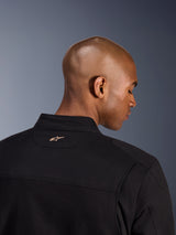 Alpinestars Bruiser Jacket, Black, back detail shot of the collar and upper shoulders, featuring a small tan embroidered Alpinestars logo on the neck, urban motorcycle jacket with workwear aesthetic