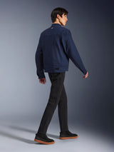 Alpinestars Bruiser Jacket in Dark Blue, urban textile motorcycle jacket, rear view on model walking, paired with black pants and gum-soled sneakers, featuring workwear-inspired design and adjustable waist tabs