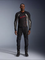Male model wearing the Alpinestars Troop-Air Jacket in Black Ash Gray and Bright Red, technical mesh motorcycle jacket featuring a prominent red chest logo, styled with black motorcycle pants and boots, urban road riding apparel
