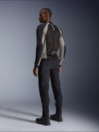 Model wearing Alpinestars Troop-Air Jacket from the back, Black Ash Gray and Bright Red accents, technical mesh construction for ventilation, paired with black motorcycle pants and riding boots, urban contemporary style