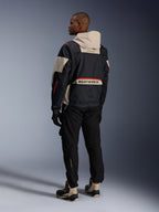 Rear view of a man wearing Alpinestars Acteon Pants in Black, paired with a Mogress Air Jacket in black and cream, black gloves, and riding boots, contemporary urban motorcycle outfit