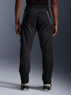 Alpinestars Acteon Pants, Urban Motorcycle Pants, Black, rear view showing tapered fit, white branding on upper legs and yellow logo on the lower calf, adjustable leg openings with zippers, worn with cream sneakers