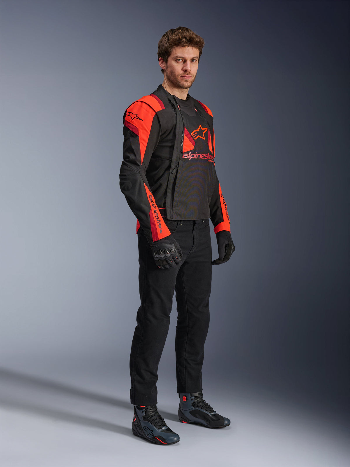 Alpinestars T-Stunt Air Jacket, Black, Red Fluo, and Dark Red, modular motorcycle jacket worn by a model with front panels open to reveal the mesh interior, paired with black riding pants, gloves, and shoes.