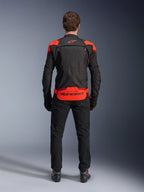 Alpinestars T-Stunt Air Jacket, Black with Red Fluo and Dark Red accents, rear view on model, paired with black riding pants and boots, featuring bold Alpinestars branding on the lower back panel, modular design with mesh construction for ventilation.