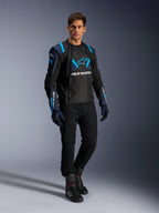 Male model wearing Alpinestars T-Stunt Air Jacket, Black Dark Blue and Blithe Blue, featuring prominent mesh panels for airflow, paired with black pants and riding gloves, sport-cut motorcycle jacket for summer road riding.