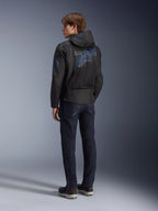 Alpinestars Zaca Air Venom WP Jacket, Black and Electric Blue, rear view on a model, mesh textile motorcycle jacket with blue Astar logo on the back, featuring a detachable hood, worn with dark jeans and black riding shoes.
