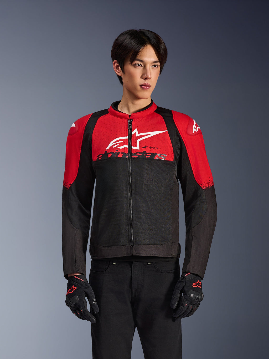 Alpinestars SMX Air Jacket, Motorcycle Mesh Jacket, Bright Red and Black, worn by a model with black riding gloves, featuring a large white logo on the chest, ventilated textile construction with red shoulder panels and black sleeves, sporty performance gear for warm-weather riding
