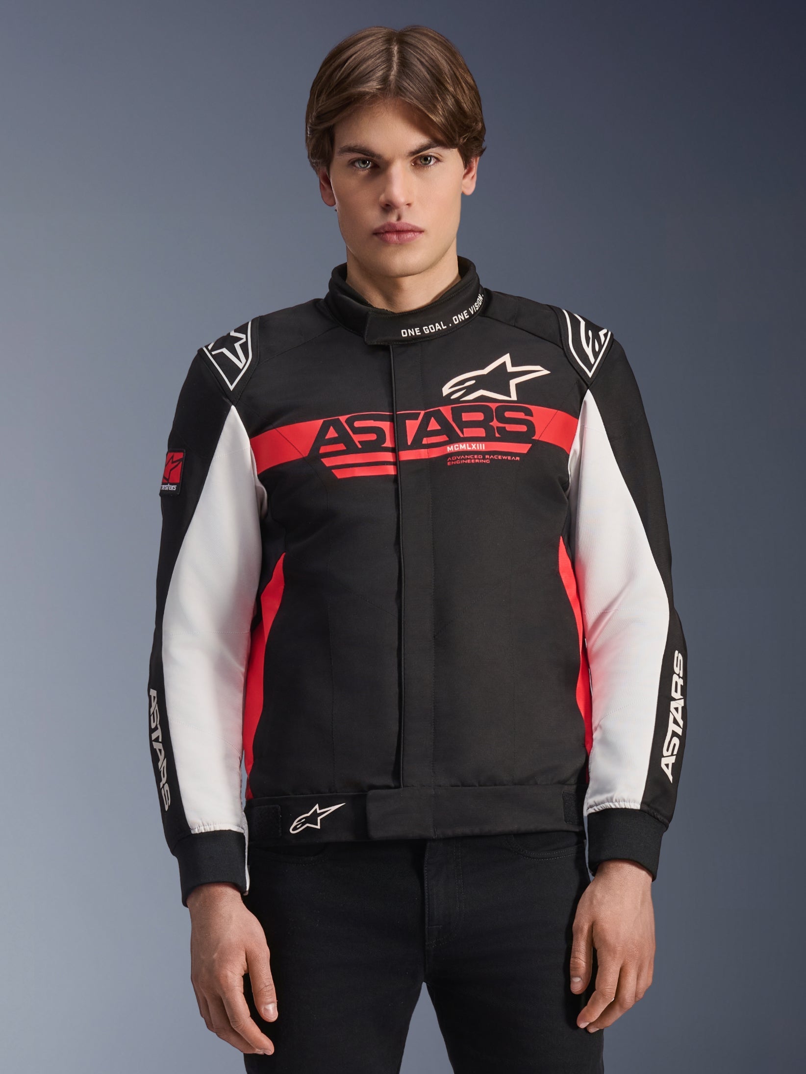 Alpinestars Monza Sport Jacket, Textile Motorcycle Jacket, Black Bright Red and White, featuring bold ASTARS chest branding, 'ONE GOAL. ONE VISION.' text on the collar, white sleeve panels, and star logos, worn by a model against a gradient background