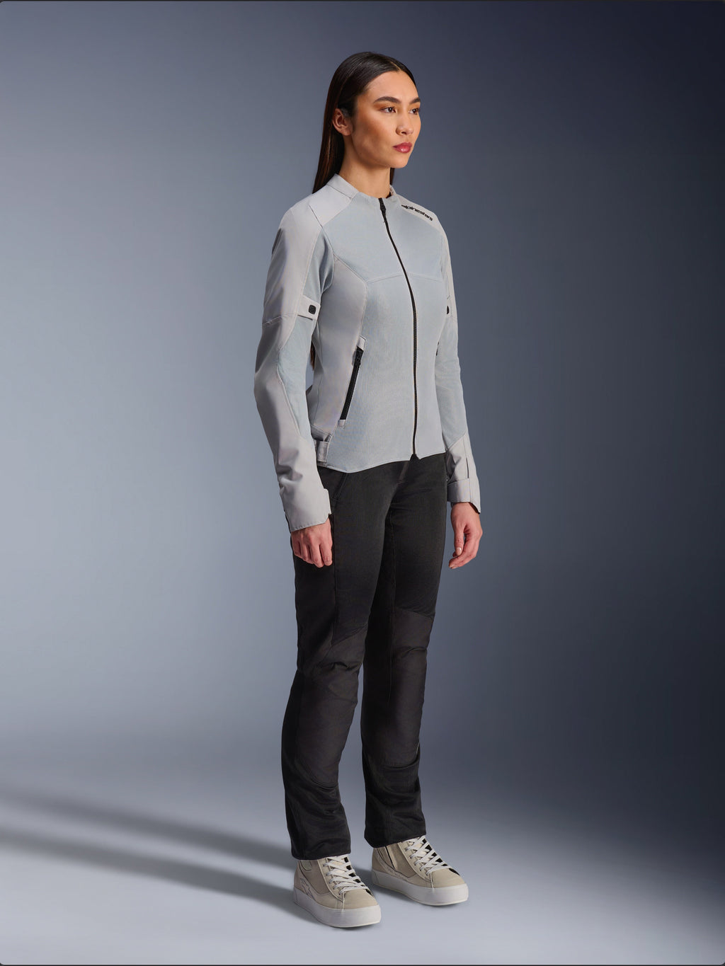 Woman wearing the Alpinestars Stella C-1 Air Jacket in Silver, lightweight textile and mesh motorcycle jacket, styled with black riding pants and casual sneakers, clean urban riding aesthetic.