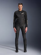 Female model wearing the Alpinestars Stella T-Dyno Air Jacket, Women's Motorcycle Jacket in Black, featuring 3D mesh panels and white Astars logos, paired with black slim-fit riding pants and black lace-up boots, urban riding gear style.