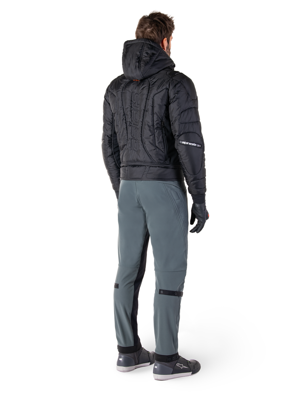 Alpinestars Alden Pants, urban motorcycle pants, Urban Gray, rear view of rider wearing a black quilted hooded jacket and riding sneakers, features slim fit below the knee with black stretch panels and knee adjusters, modern streetwear-inspired design.