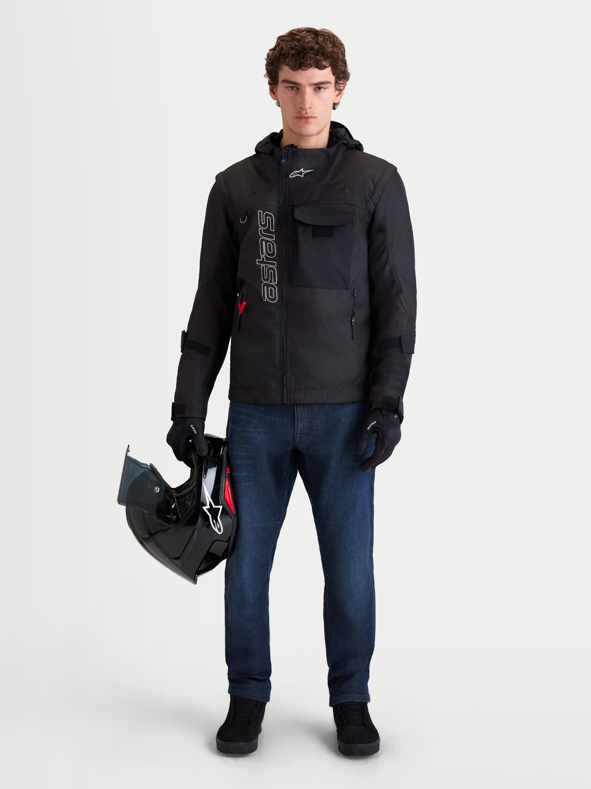 Alpinestars Flex-AST 10 Tough Max Denim Pants, men's urban motorcycle denim pants in dark blue, front view on a model wearing a black jacket and holding a helmet, AAA certified protective riding apparel.