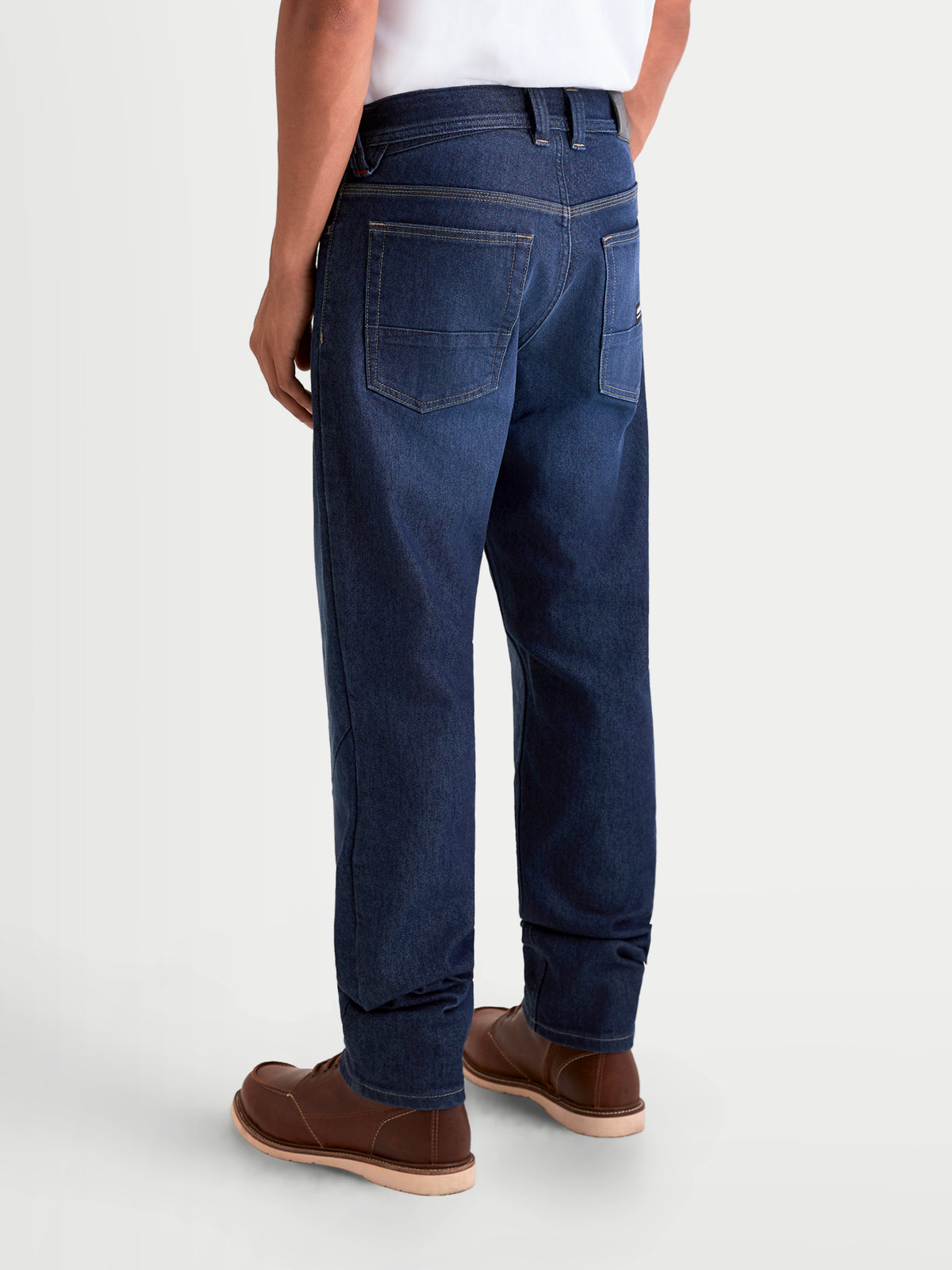 Alpinestars Flex-AST 7 Denim Pants Short, men's urban motorcycle riding jeans in dark blue, rear three-quarter view on a model wearing casual riding apparel and brown leather boots, showing single-layer technical denim construction and five-pocket styling