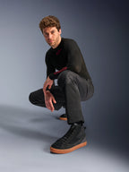 Alpinestars C-1 Air Pants, Urban Motorcycle Pants, Black, model crouching in a studio setting, worn with a black long-sleeve top and black sneakers with tan soles, featuring breathable mesh panels and a contemporary urban style