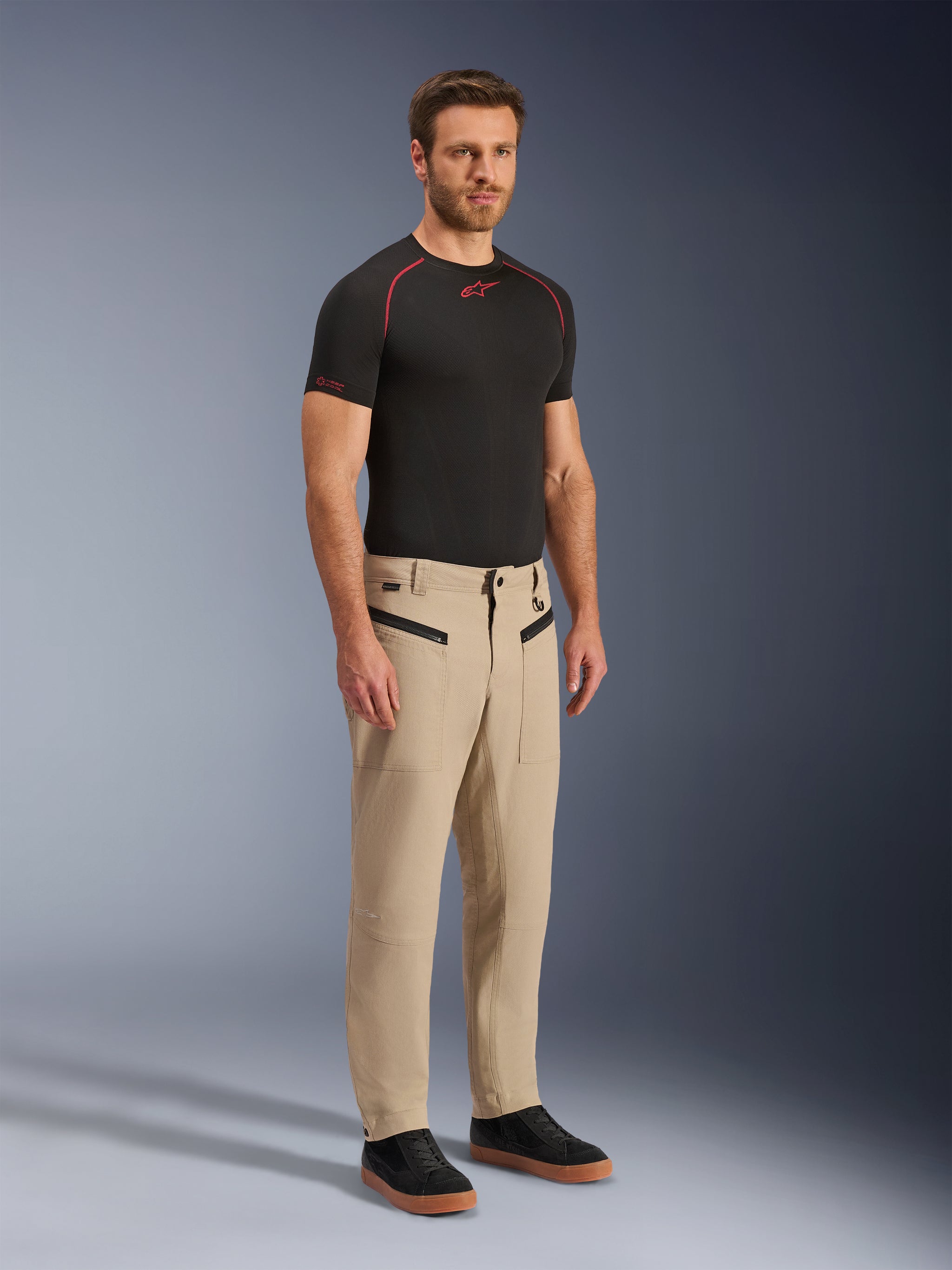 Alpinestars Flex-AST Canvas Pants, Urban Motorcycle Pants, Tan Brown, featuring heritage workwear styling with zippered front pockets and ergonomic knee panels, worn with black sneakers and a black t-shirt, contemporary urban riding gear