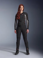 Alpinestars Stella Troop-Air Jacket and Pants, Women's Motorcycle Riding Gear, Black with Ash Gray and Pink Fluo accents, worn by a female model with red hair, featuring mesh ventilation and protective design, studio standing pose.