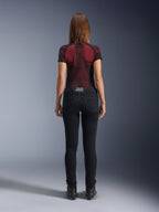 Alpinestars Daisy V3 Women's Riding Denim, Rinse Black, slim fit motorcycle pants shown from behind, featuring a high-waist design and back pockets, paired with a red and black patterned technical shirt and black boots, urban motorcycle gear for women