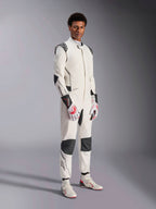 Male model wearing the Alpinestars Hypertech V3 Suit, White with Black and Silver accents, professional auto racing gear featuring black panels on shoulders and knees, styled with white and red racing gloves and white racing boots