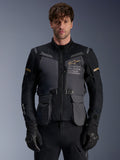 Alpinestars ST-7 2L GORE-TEX Jacket, Men's Adventure Touring Motorcycle Jacket, Deep Gray and Black with Khaki accents, featuring 'Alpinestars Exploration Equipment' branding, waterproof cargo pockets, and high collar, worn by a model with black gloves
