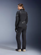 Women Stella ST-7 2L GORE-TEX Jacket, Black and Dark Gray, adventure touring jacket shown from the back, worn with matching black pants and cream boots, featuring the Alpinestars logo on the lower back, designed for all-season road touring