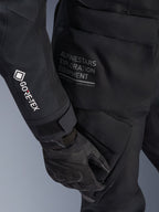 Alpinestars Women Stella ST-7 2L GORE-TEX Jacket, Black Adventure Touring Jacket, close-up view of sleeve with white GORE-TEX logo, Alpinestars Exploration Equipment text on the hip, black motorcycle glove, waterproof textile material with functional cargo pocketing