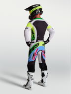 Alpinestars Supertech Dyna motocross gear in Green Fluo, Black, and Light Lilac, with racing pants and jersey, rear view.