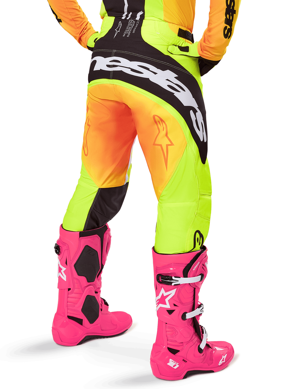 Rear view of a motocross rider wearing Alpinestars 2025 Techstar Melt Pants, Yellow and Orange gradient with black and white branding on the seat, paired with bright pink motocross boots, performance off-road gear.