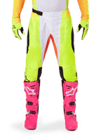 Alpinestars 2025 Techstar Melt Pants, Motocross Pants, Neon Yellow and White with Orange accents, worn with matching yellow gloves and bright pink motocross boots, features perforated ventilation panels and magnetic waist buckle, high-performance racing gear.
