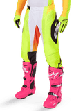 Alpinestars 2025 Techstar Melt Pants, Motocross Pants, Neon Yellow with White and Orange Accents, Black Side Patterns, worn with bright pink motocross boots and neon yellow gloves, featuring perforated ventilation, durable off-road racing gear