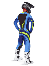 Alpinestars 2025 Techstar Melt Pants, Motocross Gear, Yellow Fluo Blue, rear view of rider wearing matching blue jersey with large yellow branding, white and black boots, and black helmet, coordinated racing outfit for off-road performance