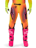 Alpinestars 2025 Supertech Lipan Pants, Motocross Pants, Orange and Yellow gradient with Pink and Black accents, worn with bright pink boots and neon yellow gloves, featuring laser-cut ventilation and a secure waist buckle, pro-level racing gear ensemble