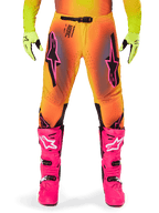 Alpinestars 2025 Supertech Lipan Pants, Motocross Pants, Orange and Yellow gradient with Pink and Black accents, worn with bright pink boots and neon yellow gloves, featuring laser-cut ventilation and a secure waist buckle, pro-level racing gear ensemble