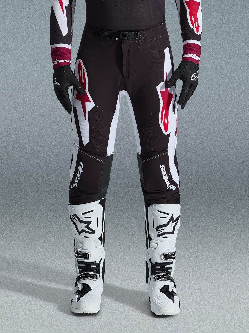 Alpinestars 2026 Supertech AFD Vista Pants, Motocross Pants, Black Red and White, featuring large graphic logos on the thighs and knees, worn with white racing boots and black gloves, athletic race-ready design for elite off-road competition