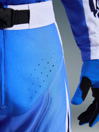 Alpinestars 2026 Techstar Knif Pants, Ucla Blue and White, close-up of hip area showing laser-cut perforations for ventilation, SX2 magnetic buckle waist closure, and matching motocross gloves
